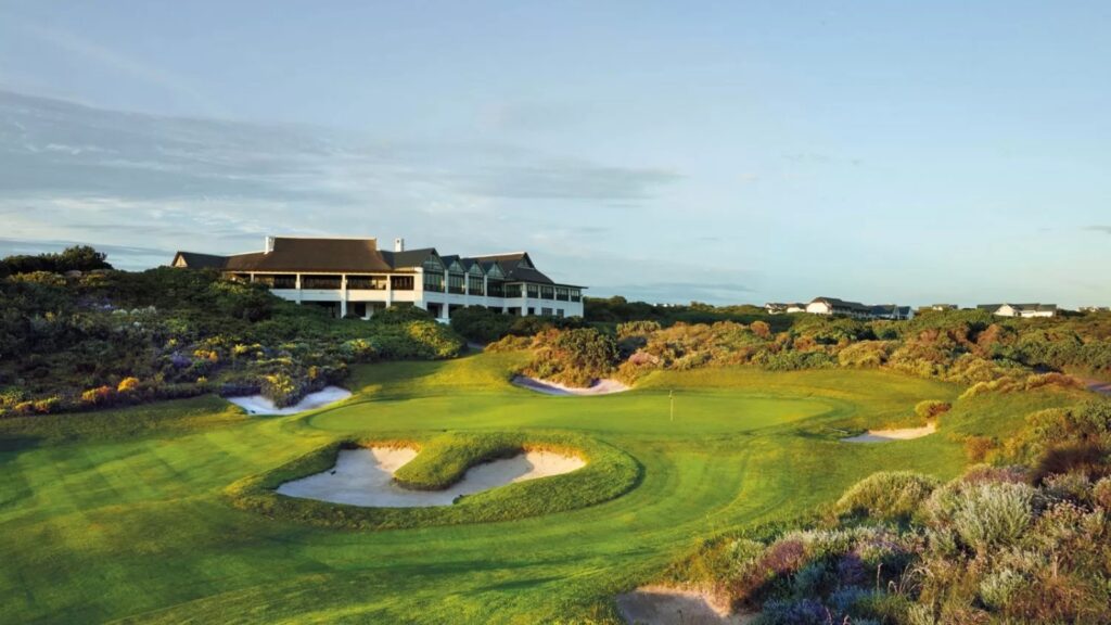 A view of a manicured putting green with the St. Francis Links clubhouse in the background.